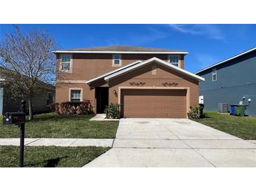 Two-story home with brown stucco exterior, well-maintained lawn, and a spacious two-car garage at 627 Lucerne Blvd, Winter Haven, FL 33881