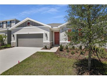 Charming home featuring a manicured lawn, stone accents, and a two-car garage at 1695 Sugarbelle Cir, Mascotte, FL 34753