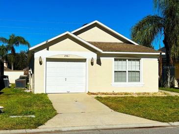 House exterior featuring a single-story home with a garage and well-maintained lawn at 2981 Kokomo Loop, Haines City, FL 33844