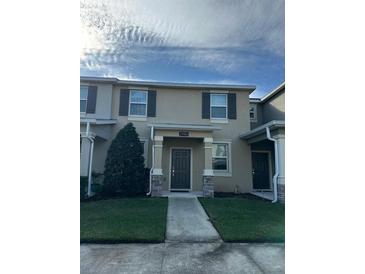 Tan two-story townhome with gray door, landscaping, and walkway at 2986 Aqua Virgo Loop, Orlando, FL 32837
