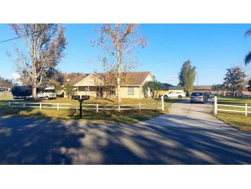 Ranch-style home with a large yard and white fence at 2831 Rodeo Dr, Kissimmee, FL 34746