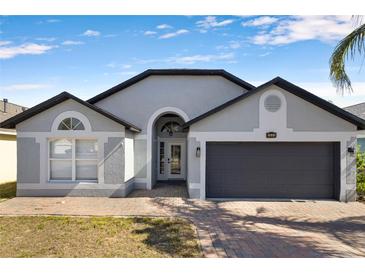 Charming single-story home featuring a two-car garage and brick-paved walkway under a clear, blue sky at 1804 Westminster Trl, Clermont, FL 34714