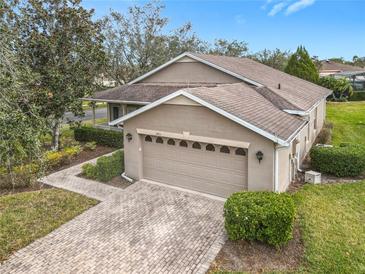 Tan house with a two-car garage and landscaped yard at 243 New River Dr, Kissimmee, FL 34759