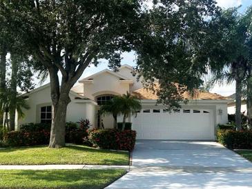 One-story home with a white exterior, two-car garage, and lush landscaping at 2835 Crane Trace Cir, Orlando, FL 32837