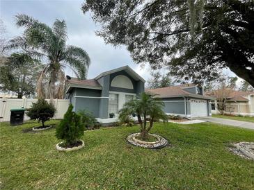 Cute one-story house with gray exterior, landscaped lawn, and a two-car garage at 3215 Timucua Cir, Orlando, FL 32837