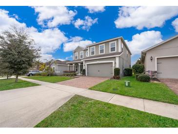 Two-story house with gray siding, brick driveway, and landscaped lawn at 437 Seattle Slew Dr, Davenport, FL 33837