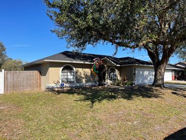 Single-story home with a large tree, attached garage, and fenced yard at 511 Kilimanjaro Dr, Kissimmee, FL 34758