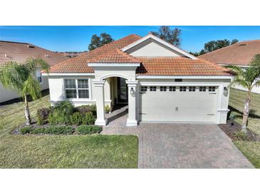 Single-story house with tile roof, two-car garage, and landscaped front yard at 8899 Fallen Oak Dr, Davenport, FL 33836