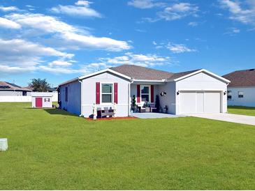 Gray house with red shutters, landscaping, and detached shed at 905 Desmoines Way, Poinciana, FL 34759