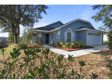 One-story house with blue exterior, landscaped yard, and attached garage at 201 Steamboat Blvd, Davenport, FL 33897