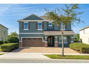 Two-story house with a green facade, brown garage door, and a well-manicured lawn at 370 Burma St, Kissimmee, FL 34747