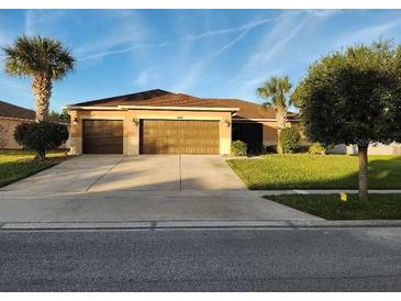 Tan three-car garage house with a neatly landscaped lawn at 4047 Marina Isle Dr, Kissimmee, FL 34746