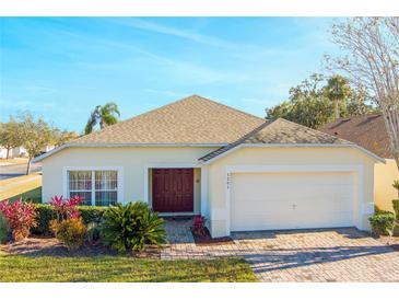 One-story house with a brown door, attached garage, and well-manicured lawn at 1201 Winding Willow Ct, Kissimmee, FL 34746