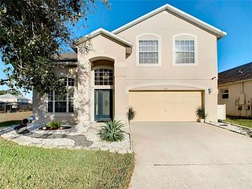 Two-story house with a two-car garage and landscaping at 124 Cassia Dr, Davenport, FL 33897