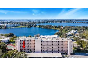 Aerial view of lakefront condo building with pool and tennis courts at 1776 6Th St Nw # 209, Winter Haven, FL 33881