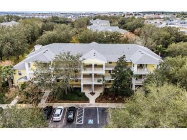 Aerial view of a yellow building with multiple units, parking, and landscaping at 312 Lucaya Loop # B5/U312, Davenport, FL 33897