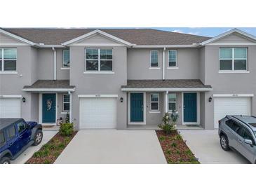 Three-unit townhome building with gray exterior, two-car garages, and landscaping at 4078 Malawi Trl, Saint Cloud, FL 34772