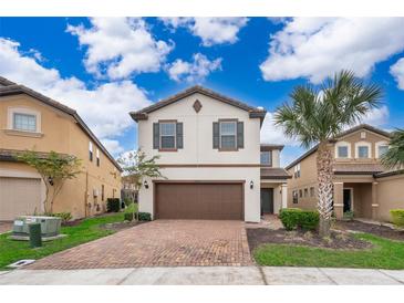 Two-story house with brown garage door and brick driveway, surrounded by palm trees at 5505 Misty Oak Cir, Davenport, FL 33837