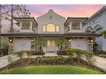 Elegant two-story home featuring twin garages, balconies, landscaped garden, and a beautiful sky at sunset at 8162 Valhalla Ter, Reunion, FL 34747