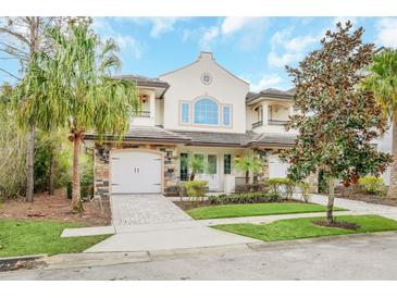 Elegant two-story townhome featuring a stone facade, arched windows, and lush landscaping in a well-maintained community at 8162 Valhalla Ter, Reunion, FL 34747