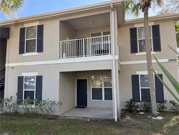 Two-story condo building with light beige exterior, dark gray shutters, and a private balcony at 3011 Hemingway Cir # 3011, Haines City, FL 33844