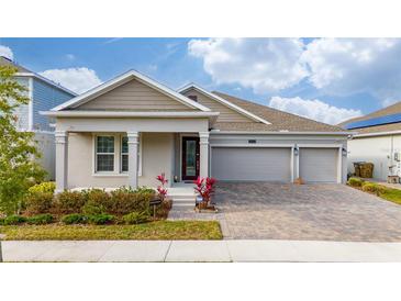 Two-story house with gray siding, three-car garage, and landscaped front yard at 3052 Ella Way, Saint Cloud, FL 34771