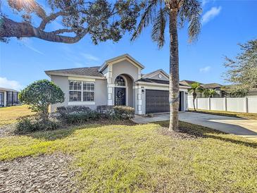 Single-story house with gray exterior, dark garage door, and palm tree at 370 Henley Cir, Davenport, FL 33896