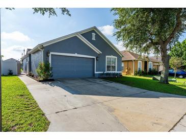Charming blue home featuring an attached garage and well-manicured lawn at 435 Madina Cir, Davenport, FL 33837