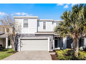 Two-story house with gray siding, stone accents, and a gray garage door at 8953 Zurich Ln, Kissimmee, FL 34747