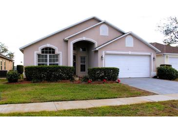 Tan house with white garage door and landscaping at 1068 Lake Berkley Dr, Kissimmee, FL 34746