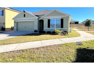 One-story house with green exterior, two-car garage, and landscaped yard at 120 Panda Way, Davenport, FL 33837
