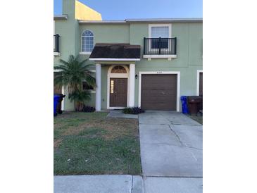 Two-story townhome with a green exterior, brown garage door, and small front yard at 4372 Paradise Cove Ct, Kissimmee, FL 34746