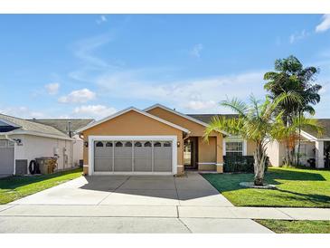 Tan house with a two-car garage and well-maintained lawn at 4612 Osceola Point Trl, Kissimmee, FL 34746