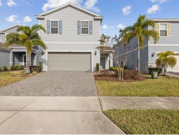 Two-story house with gray siding, two-car garage, and a landscaped front yard at 1607 Kona Ln, Davenport, FL 33897