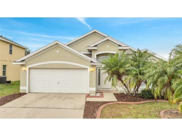 Tan house with white garage door, landscaping, and palm trees at 2318 Andrews Valley Dr, Kissimmee, FL 34758