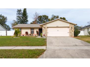 Tan one-story house with pink garage door and stone accents. Landscaped yard at 3618 Willow Lake Ct, St Cloud, FL 34769