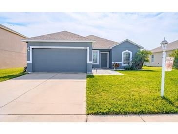 Charming one-story home with a well-manicured lawn, two car garage, and neutral blue paint at 6144 Forest Ridge Way, Winter Haven, FL 33881
