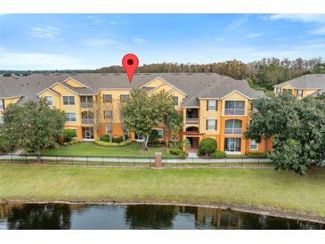 Exterior view of a two-story condo building with water features and landscaping at 8660 Buccilli Dr # 305, Orlando, FL 32829