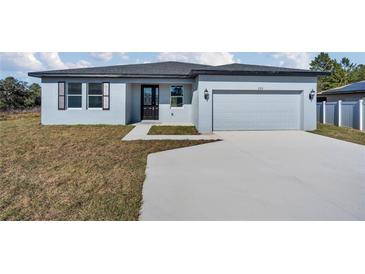 New construction home with gray exterior, two-car garage, and driveway at 223 Elm Ct, Kissimmee, FL 34759