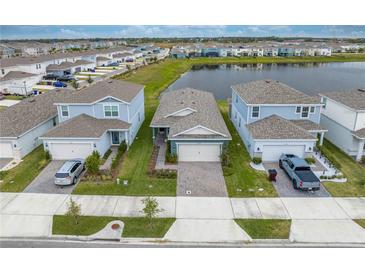 Aerial view of three homes with two-car garages, and a community lake at 2589 Autumn Peace Dr, Kissimmee, FL 34744