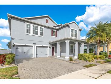 Two-story house with gray siding, two-car garage, and landscaped yard at 3074 White Horse Ct, Kissimmee, FL 34746