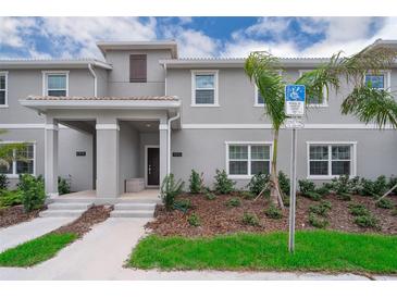 Two-story townhome with light gray exterior, walkway, and landscaping at 4816 Memories Ln, Kissimmee, FL 34746