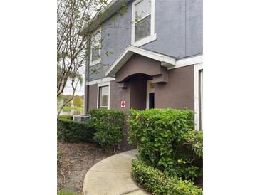 Two-story townhome with brown door and gray siding, landscaped walkway at 6660 S Goldenrod Rd # 126B, Orlando, FL 32822