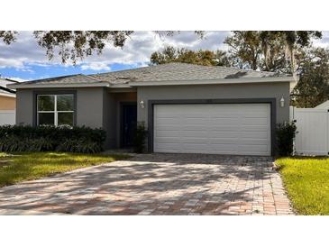 Gray house with white garage door and a brick driveway at 115 W Murphy St, Davenport, FL 33837