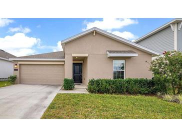 Tan house with black door, two-car garage, and manicured lawn at 1274 Fury St, Davenport, FL 33837
