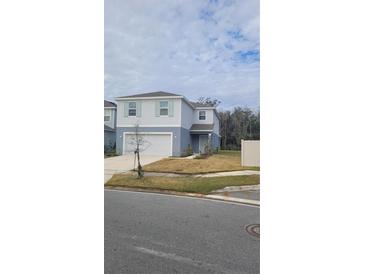 Two-story house with light gray siding, white garage door, and landscaping at 1511 Woodmont Blvd, Kissimmee, FL 34746