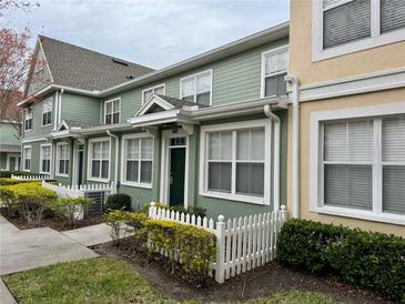 Two-story townhome with green siding, white picket fence, and landscaping at 2200 San Christabolo Dr # 106, Kissimmee, FL 34741