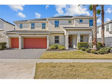 Two-story house with orange garage doors and a landscaped lawn at 2612 Yountville Ave, Kissimmee, FL 34741