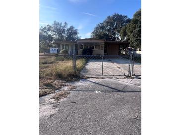 Tan single-story home with carport and chain link fence at 34429 Laralack Ave, Leesburg, FL 34788