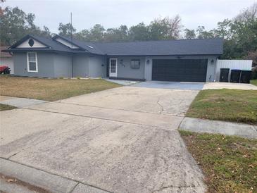 Cozy one-story home featuring a gray exterior, black garage door, and spacious driveway at 4749 Hopespring Dr, Orlando, FL 32829